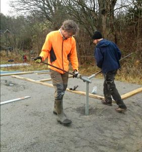 Två personer skruva ner en skruvpåle med verktyget SR100