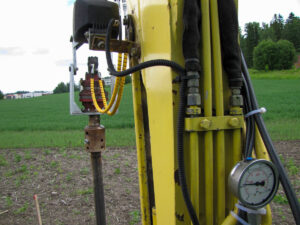 En hydraulisk rotator med oljetrycksmätare, använd för att övervaka trycket vid skruvpåleinstallation enligt en specifik trycktabell.