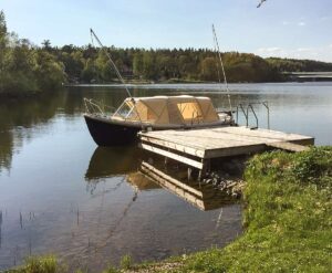 En Crescent snipa båt förtöjd med Mooring Whips vid en träbrygga i en lugn sjöomgivning.