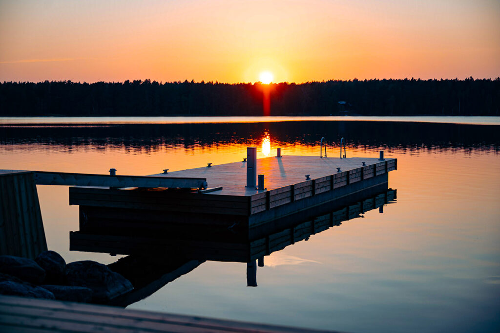 Flytbrygga i lugn sjö vid solnedgång med skyddad bryggkant