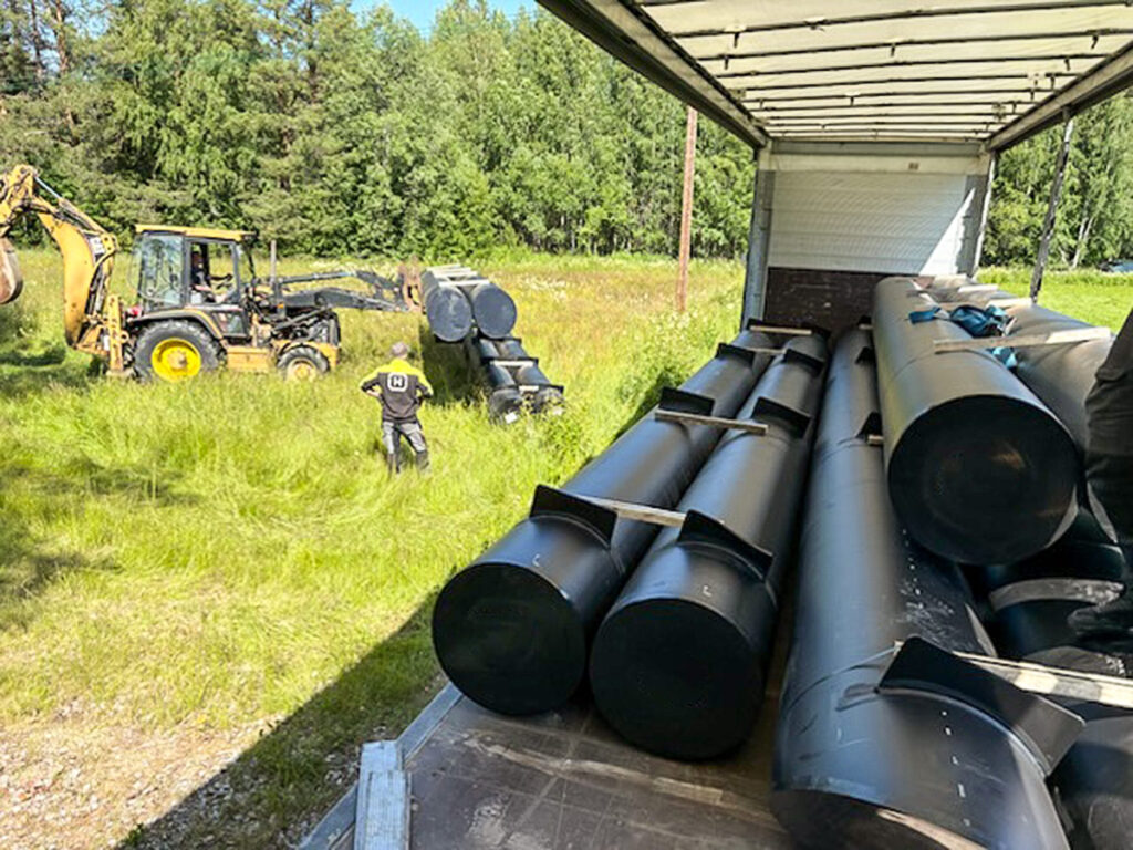 Långa rörpontoner i HD-polyeten transporteras på lastbil.