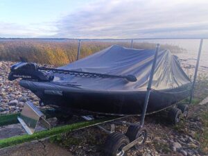 Roller 2000XR båtvagn med åtta hjul och en täckt motorbåt uppställd på stenig strand.