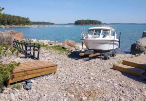 Finnmaster 61 på Roller XR-båtvagn på stenig strand vid havet.