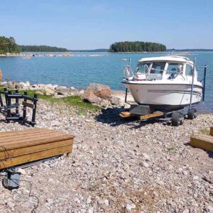 Finnmaster 61 på Roller XR-båtvagn på stenig strand vid havet.